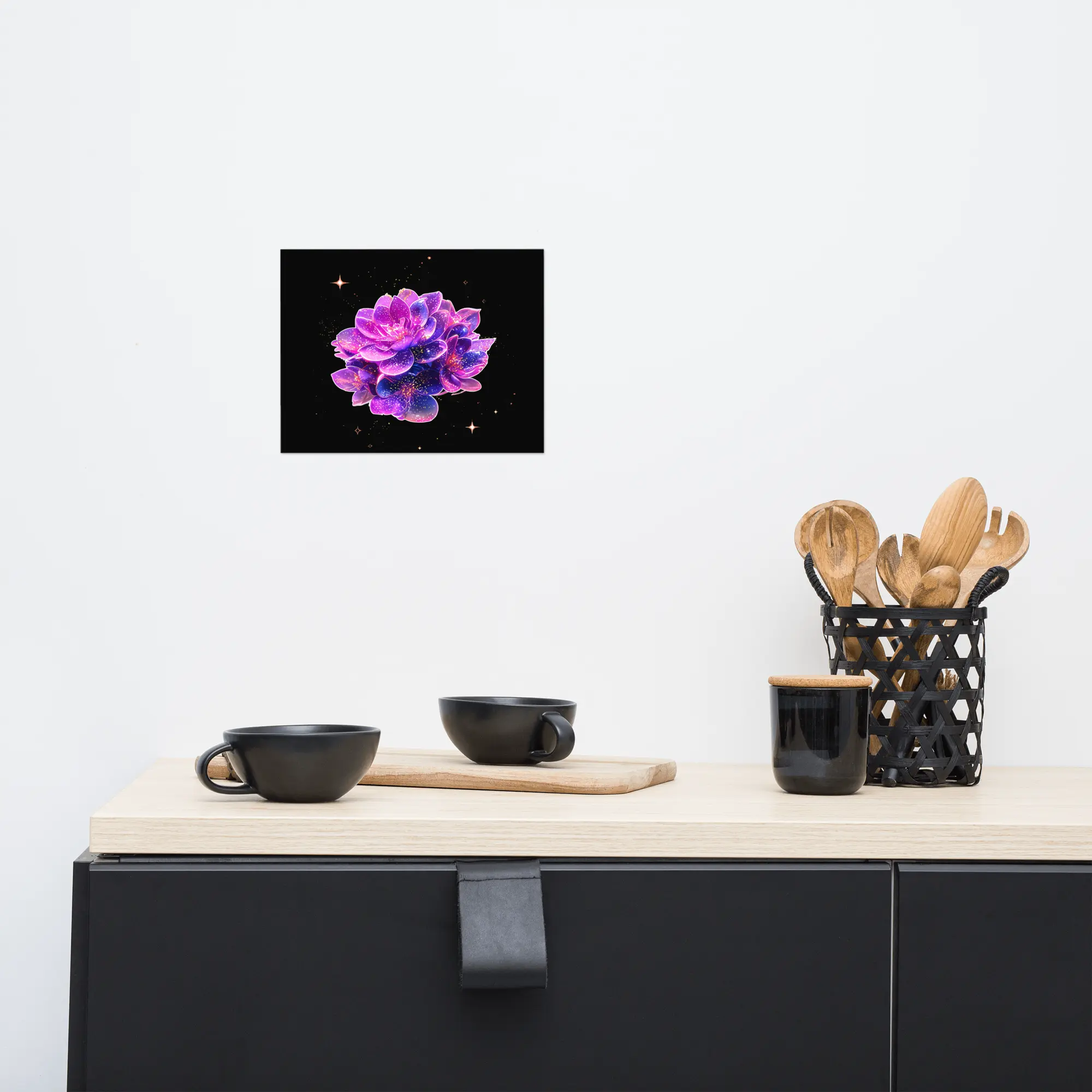 Kitchen countertop with a black cabinet, light wood surface, and wooden utensils, with a purple floral galaxy Stardust Lotus poster hanging above on a white wall. Feyflora
